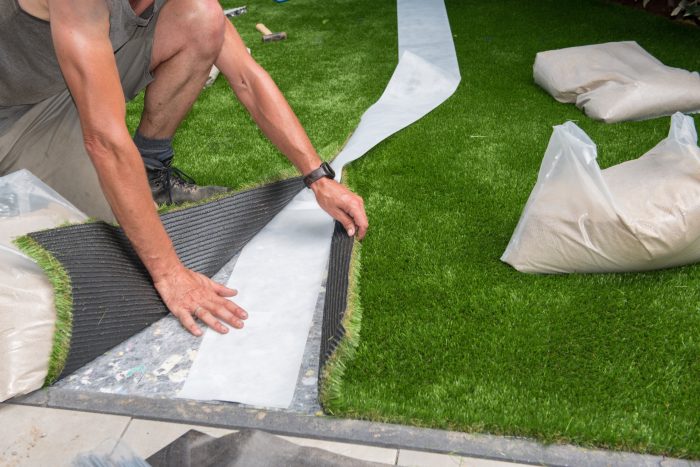 laying out artificial grass to cut